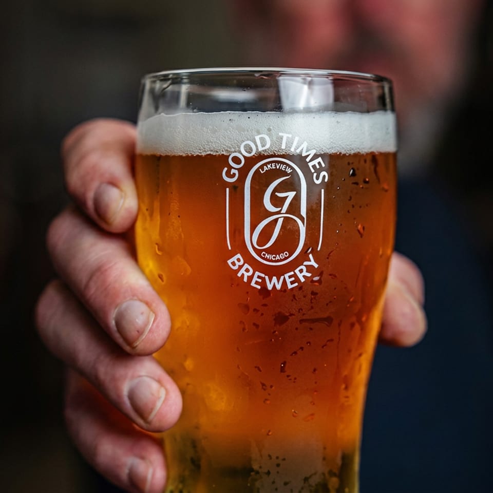Hand holding a condensation-covered pint of amber beer with a foamy head in a Lakeview Brewery glass.